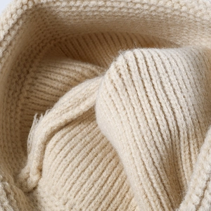 Detailopname van beige gestreepte gebreide muts met zachte wol en ribbelpatroon