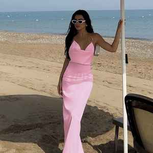 Détail d'une robe maxi en satin rose élégante avec col bénitier dans un décor de plage