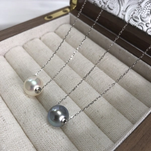 Detailed close-up of double-tone pearls on a silver chain inside a luxury wooden jewelry box