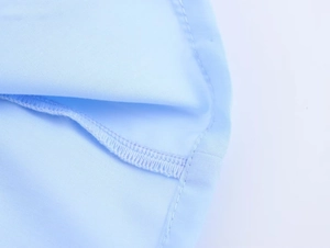 Gros plan détaillé des coutures et du tissu bleu clair lisse d'un chemisier pour femme
