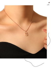 Close-up of a rose gold necklace with a number 7 rectangle pendant on a snake chain