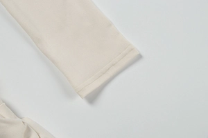 Close-up of the beige knit dress cuff showing precise double-needle stitching detail