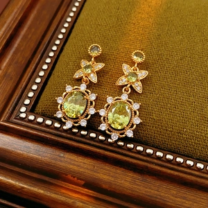 Détail de boucles d'oreilles vintage en or avec zircons jaunes sur velours vert