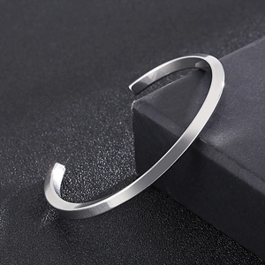 Vue rapprochée d'un bracelet torsadé argenté en acier sur un coffret cadeau de luxe