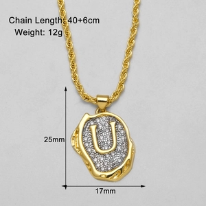 Detail der goldenen Kordelkette mit funkelndem, diamantbesetztem Buchstaben-U-Anhänger