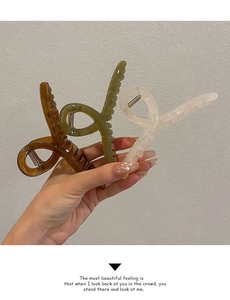 Close-up of three large resin hair claws in amber, olive green and cream colors