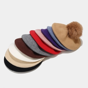 Detail view of multi-color knitted berets with fluffy fox fur pom-poms in various colors