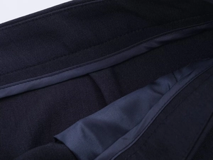Detailed close-up of dark blue suit fabric with twill texture and premium inner stitching