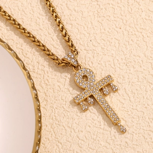 Detailed view of an 18K gold plated key pendant with rhinestones on a twisted chain