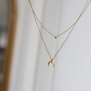 Close-up of double-layer gold titanium necklace with green stone and crescent moon pendant
