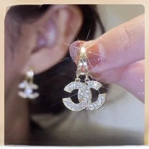 Detailed macro view of gold-tone double C earrings encrusted with sparkling crystals