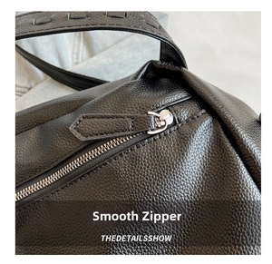 Detail of high-quality smooth metal zipper on textured black leather tote bag close-up