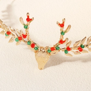 Macro detail of golden Christmas reindeer hairclip with red and green beads and leaf patterns