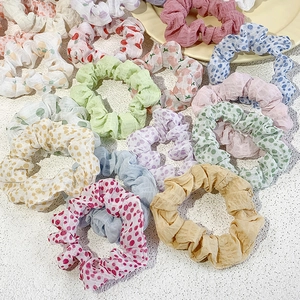 Flat lay of colorful floral and polka dot chiffon scrunchies on white tabletop