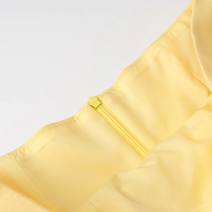 Détail de la fermeture éclair invisible sur l'ensemble plissé jaune en tissu soyeux