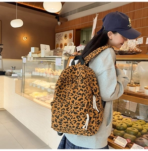 Leopard print corduroy backpack featuring front zipper pocket and white rope pulls