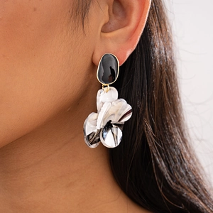 Gros plan de boucles d'oreilles florales en résine marbrée noire et blanche sur mannequin