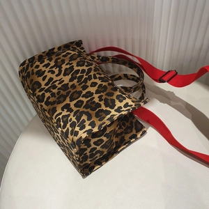 Close-up of leopard print canvas tote bag with adjustable red shoulder strap detail