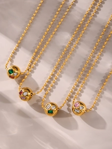 Gros plan de colliers à billes dorées avec pendentifs sphériques sertis de gemmes