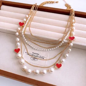 Multi-layer vintage gold necklace with white faux pearls on a beige velvet display tray