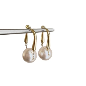 Minimalist gold dangle earrings featuring elegant white pearls and a wavy metallic design