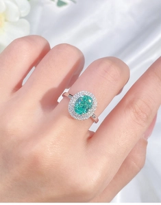 Macro detail of oval green gemstone ring with double halo diamond setting on hand