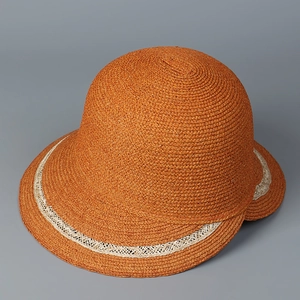 Detail of caramel raffia cloche hat featuring a cream hollow-out woven decorative band