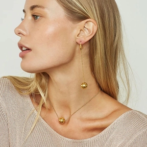 Ensemble collier avec pendentif boule dorée et boucles d'oreilles sur mannequin