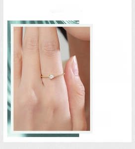 Detail of twisted gold ring featuring a drop-shaped white zircon and beaded texture