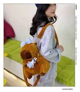 Detail of Capybara plush backpack with blue checkered bow and bunny pendant charm