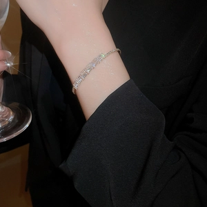 Detail of square-cut zircon stones on a silver bangle held with a glass