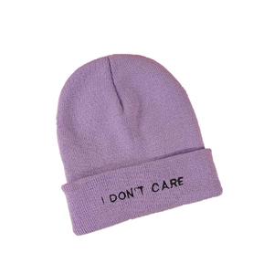 Detail of I DON'T CARE embroidery on light purple knitted beanie with ribbed texture