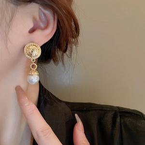 French vintage gold circle earrings with white pearl pendants worn by a model