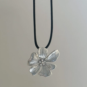 Detail of flower pendant with 18k gold plating, textured petals and micro zircon inlay
