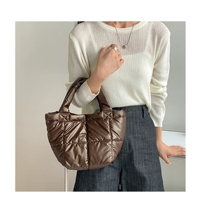 Detail of a dark brown quilted down tote bag with a glossy finish and soft texture