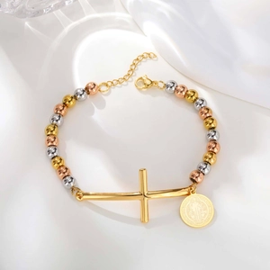 Detailed shot of tricolor beaded bracelet featuring gold cross and Saint Benedict medal