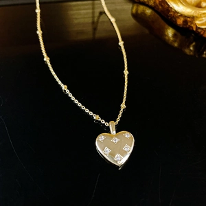 Détail du collier cœur doré orné de zircons avec une chaîne à billes délicate et élégante