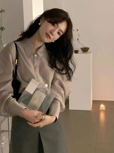 Detail showing elegant pearl earrings paired with an oatmeal long-sleeved shirt and skirt