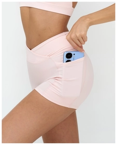 Detail of high-waisted yoga shorts with side pocket and criss-cross waistband design