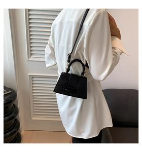 Mannequin portant un mini sac trapèze noir en cuir grainé avec poignée et bandoulière