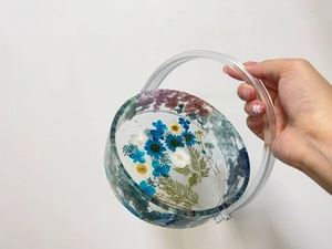 Detail of round resin tote mold showing embedded dried flowers and clear handle