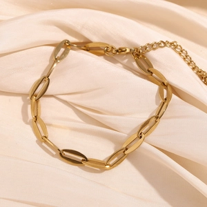 Detail view of 14K gold plated lip chain bracelet with lobster clasp on silk fabric