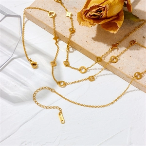 Elegant gold clover multi-layer stainless steel necklace set on a textured stone base