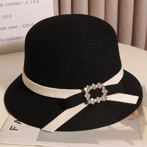 Détail d'un chapeau en laine noire avec ruban blanc et boucle de luxe en strass