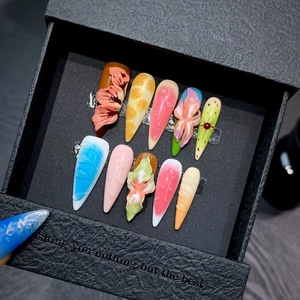 Macro shot of colorful 3D flower press-on nails with stiletto shape in a black gift box