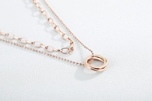 Macro view of rose gold double-layer necklace with interlocking rings and mixed chains