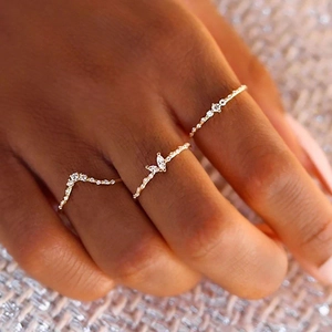 Close-up of three gold-plated stackable rings with sparkling marquise and V-shaped zircons