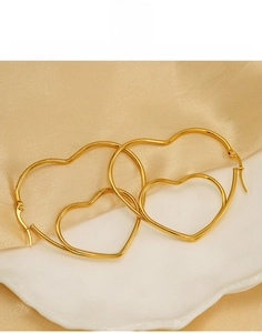 Détail de boucles d'oreilles double cœur en acier titane doré à structure creuse