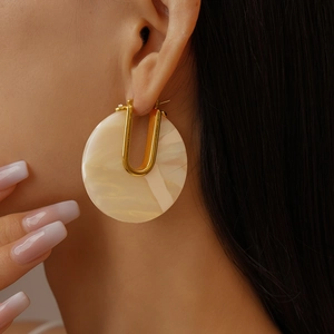 Close-up of 18k gold plated U-shaped earring with pearlescent acetate finish on model