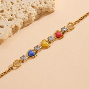Bracelet doré avec coeurs en émail coloré et zircons étincelants sur fond beige doux